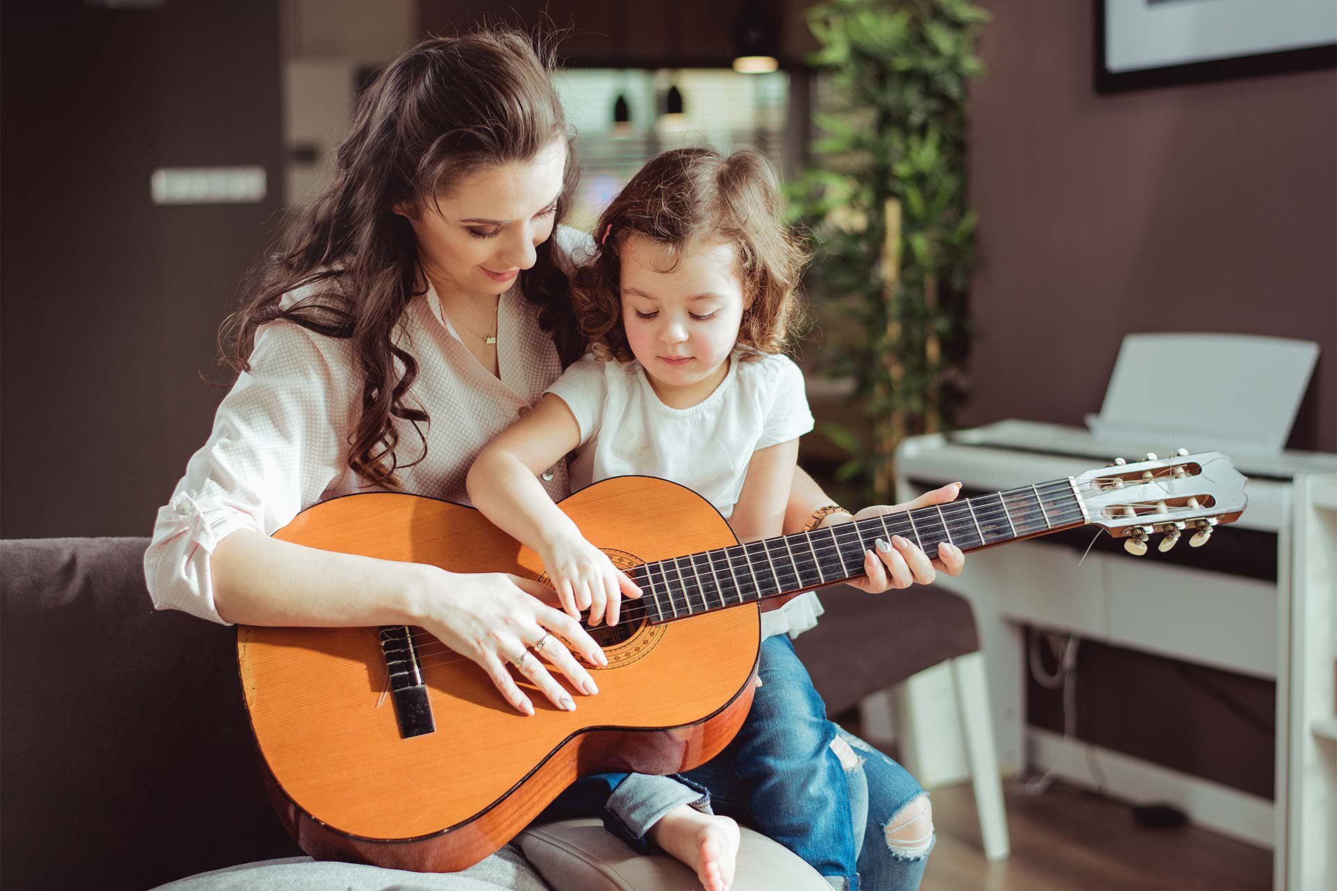 Mamá enseñando a su hija a tocar guitarra