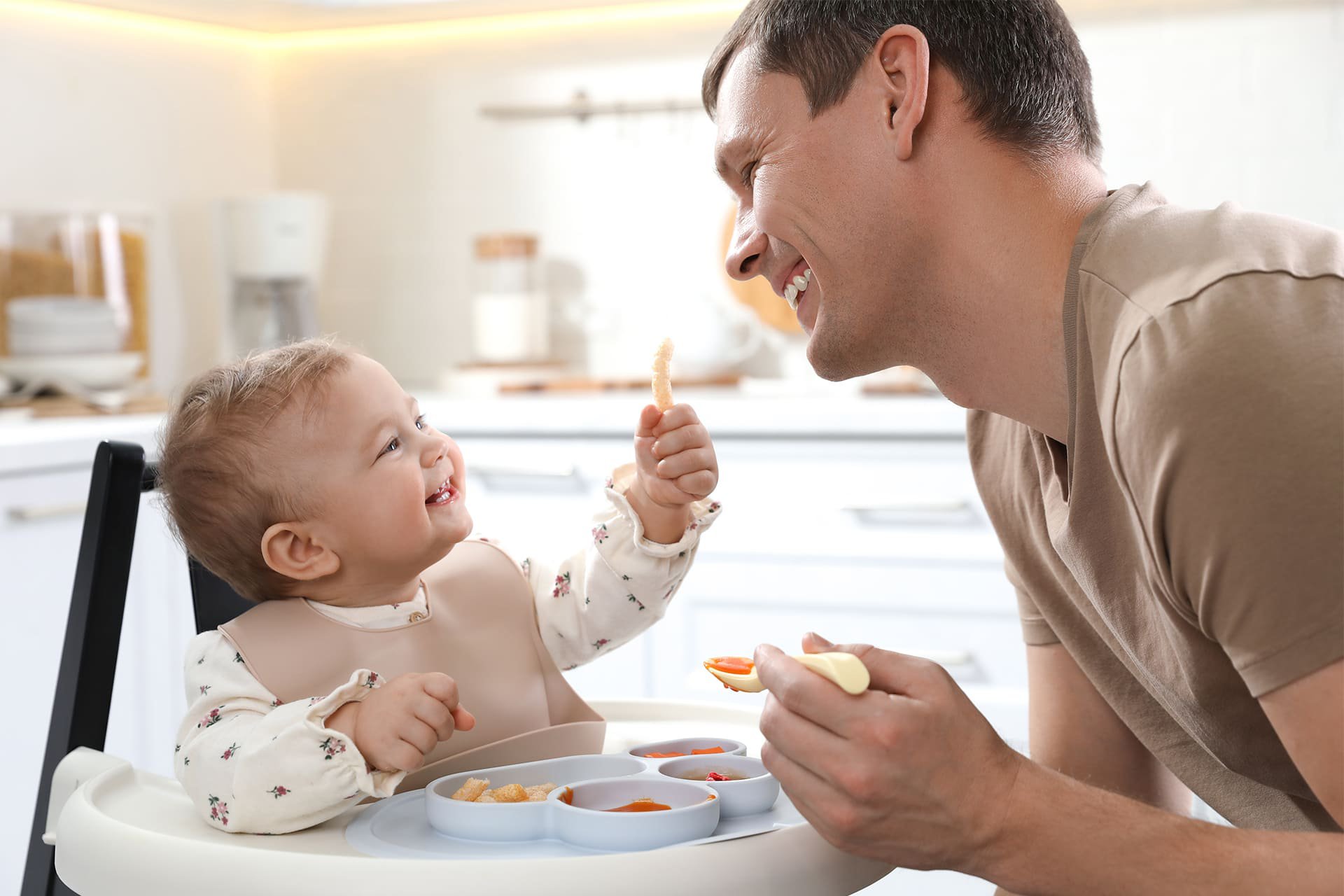Papá enseñando a su bebé a comer solo