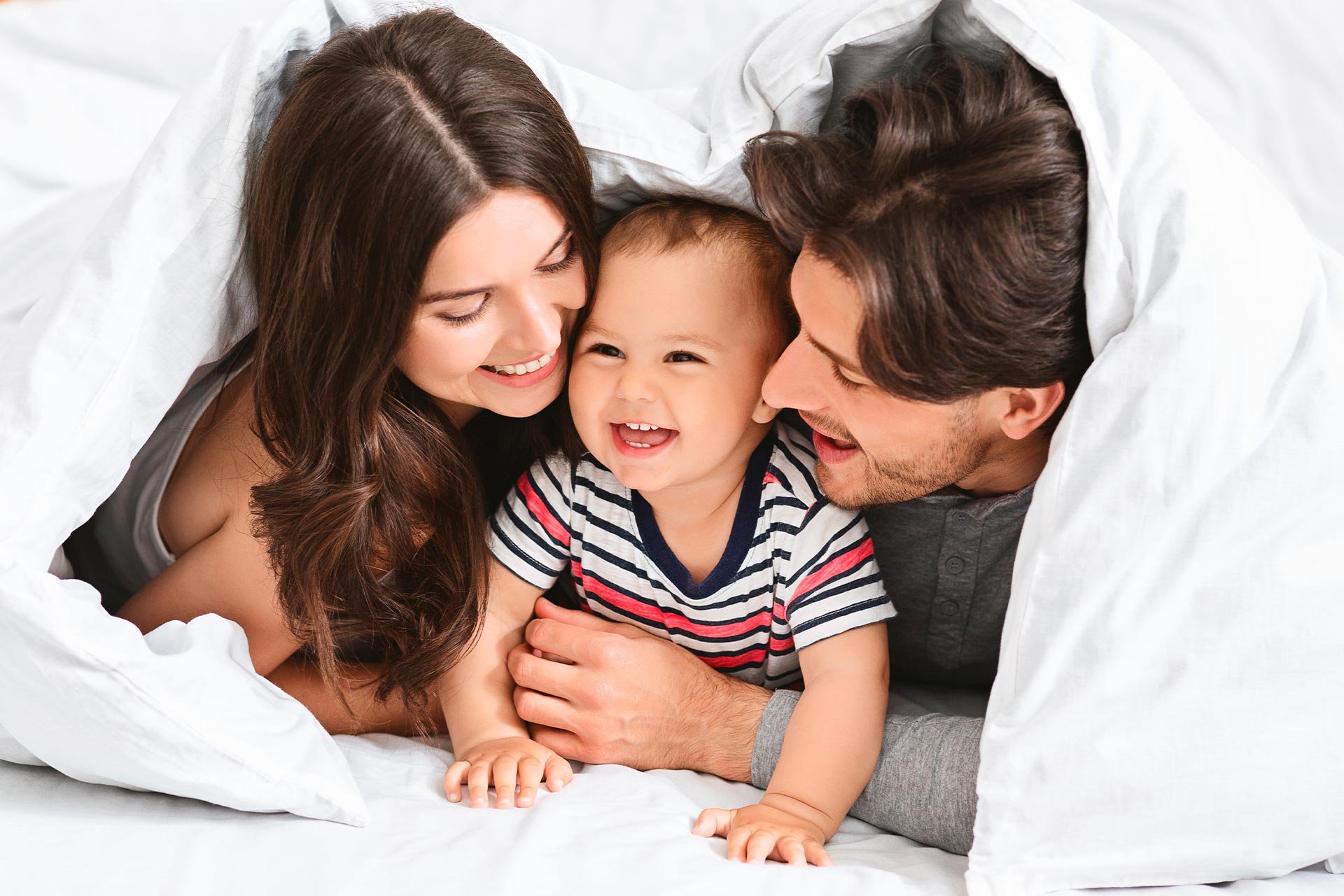 Bebé sonriendo con su papá y su mamá