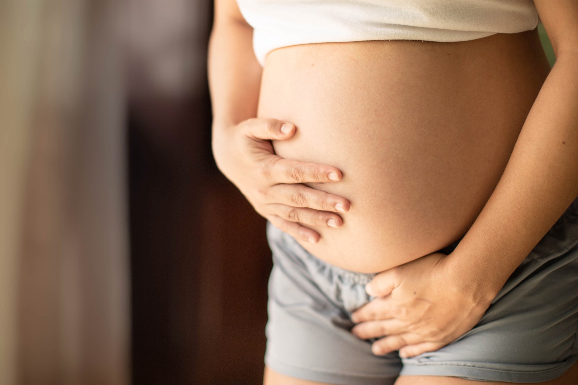 Mujer embarazada presionando su barriga.