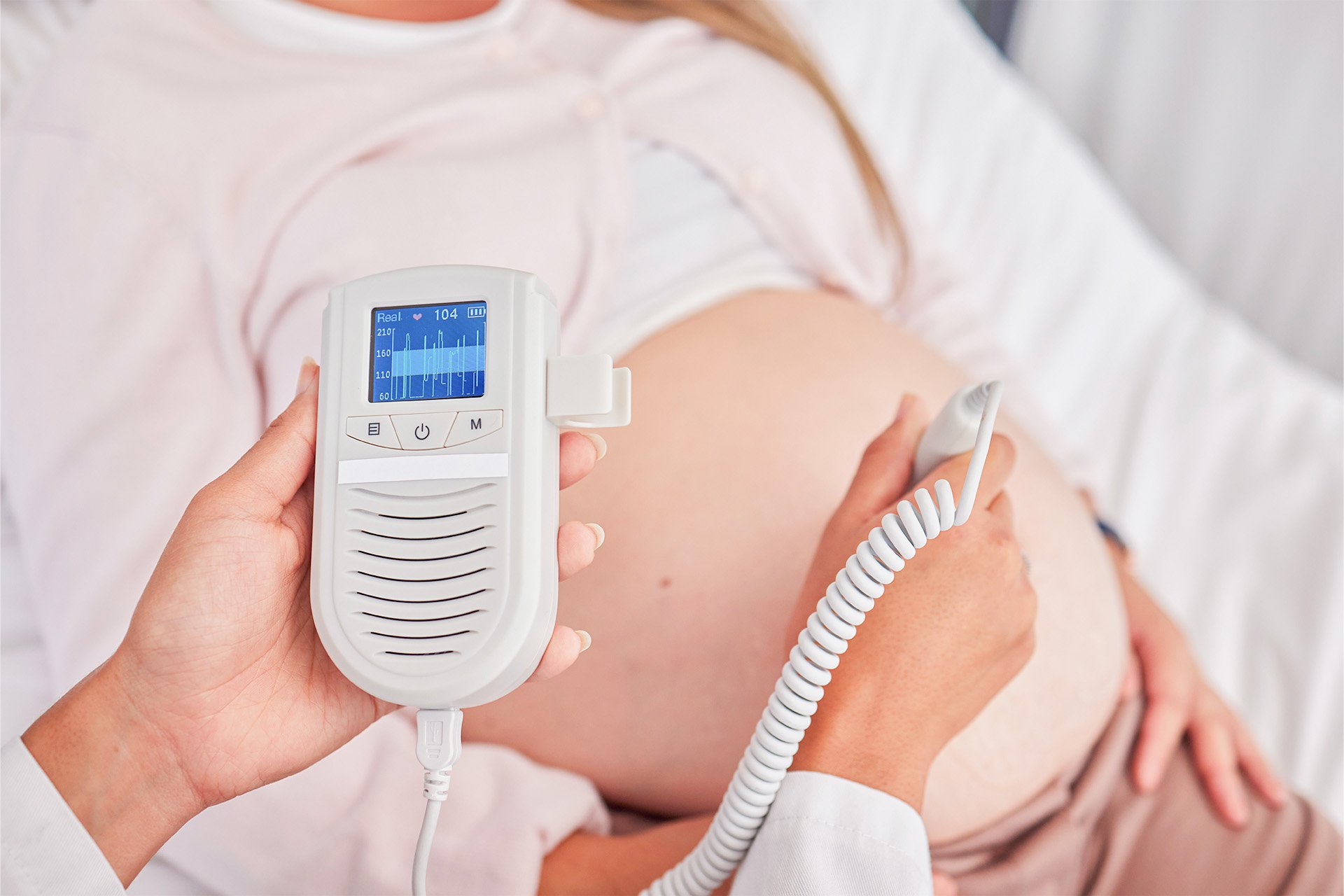 Médico midiendo la frecuencia cardiaca fetal a una mujer embarazada.