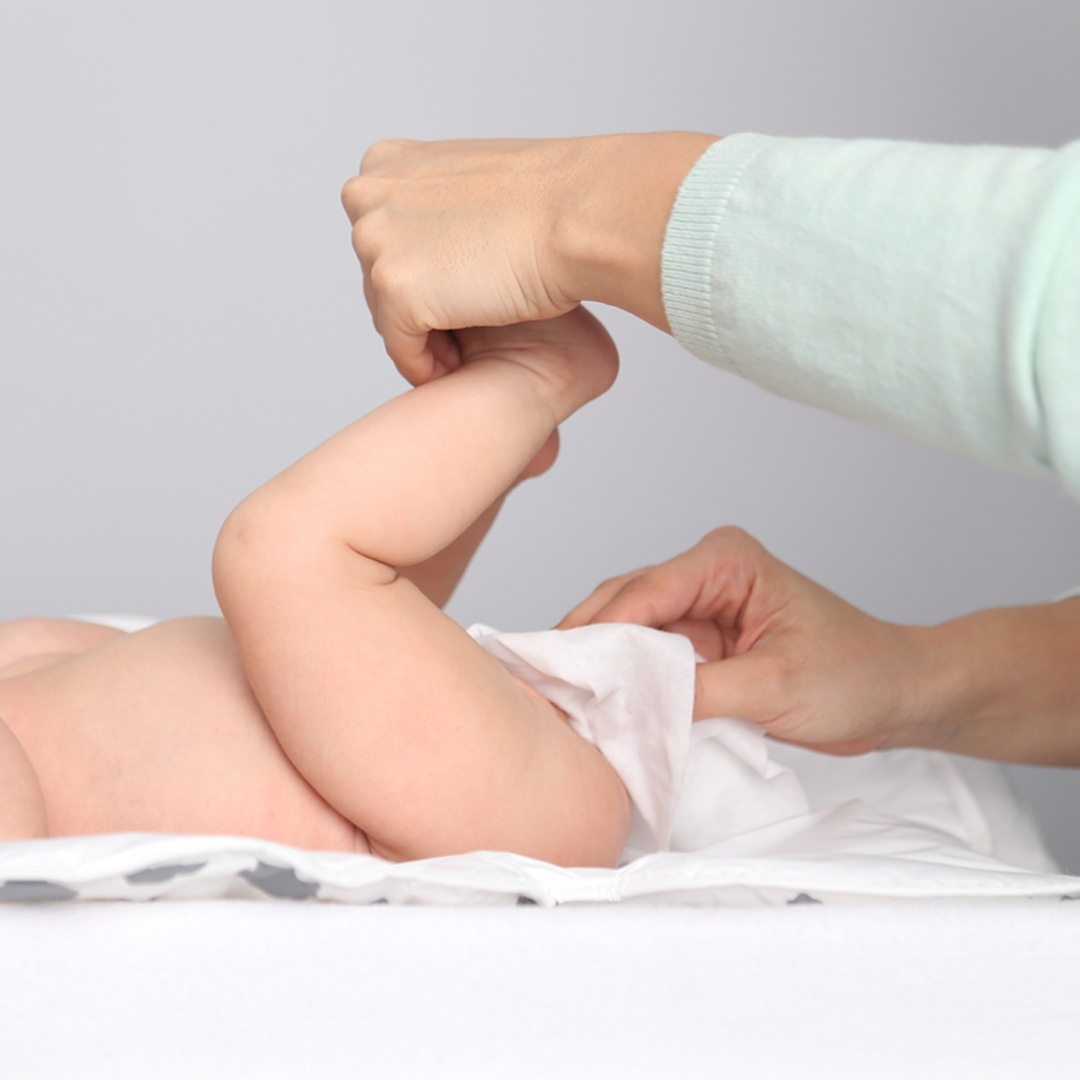 Mamá limpiando la colita de su bebé.